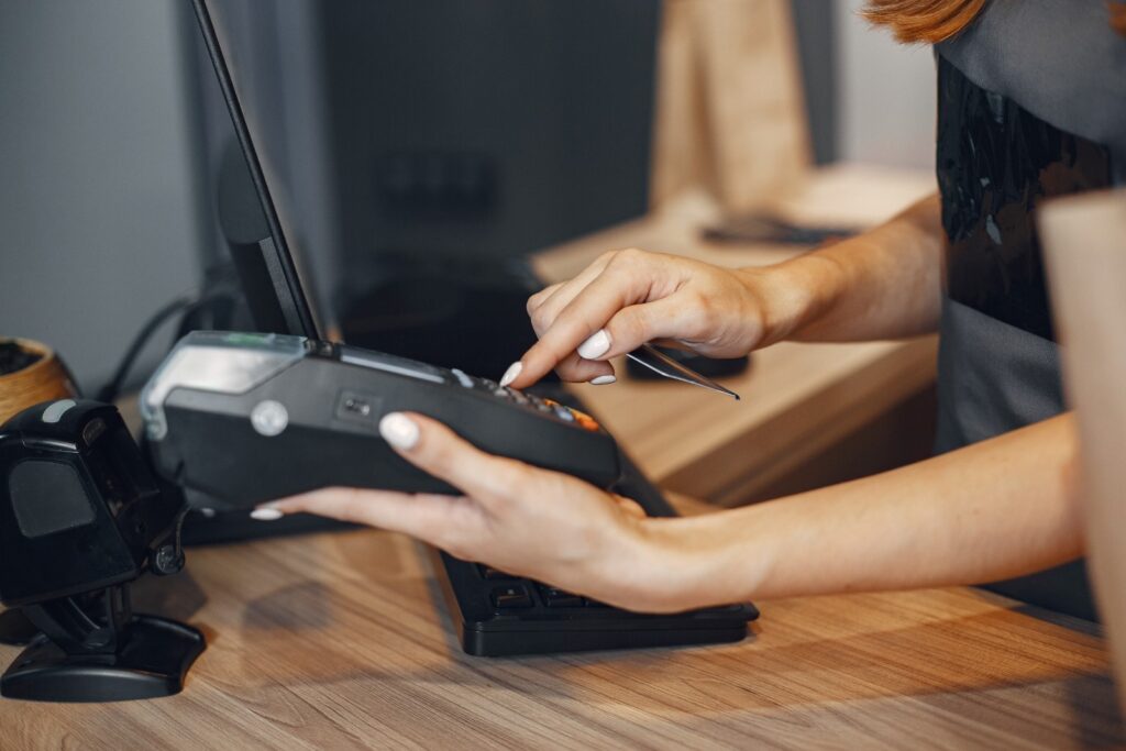 Cashier entering payment on a card reader terminal at a retail counter.