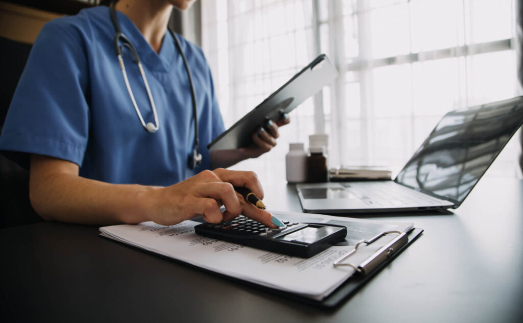 serious-female-doctor-using-laptop-writing-notes-medical-journal-sitting-desk-young-woman-professional-medic-physician-wearing-white-coat-stethoscope-working-computer-workplace
