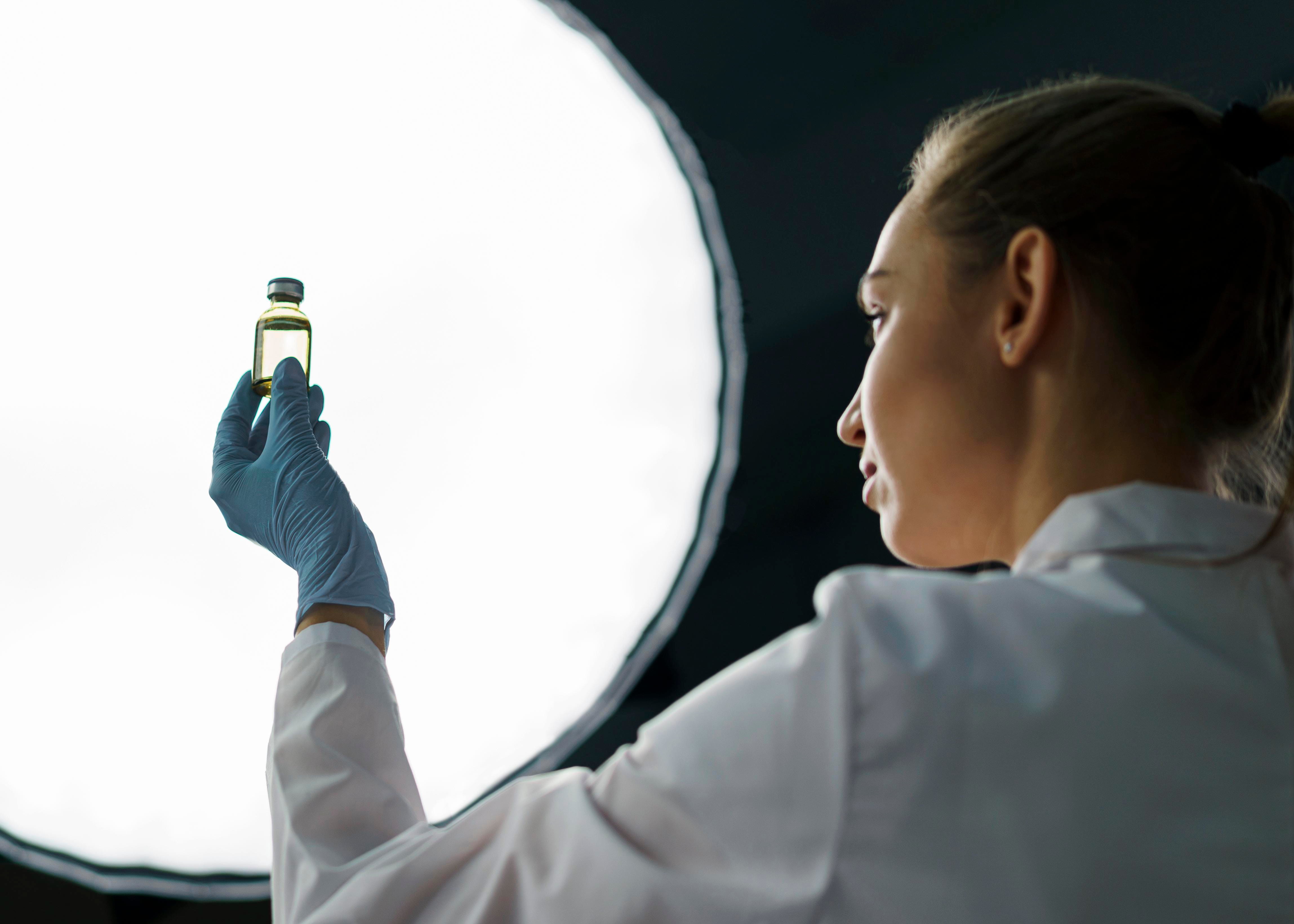 female-researcher-laboratory-holding-vaccine-bottle-light