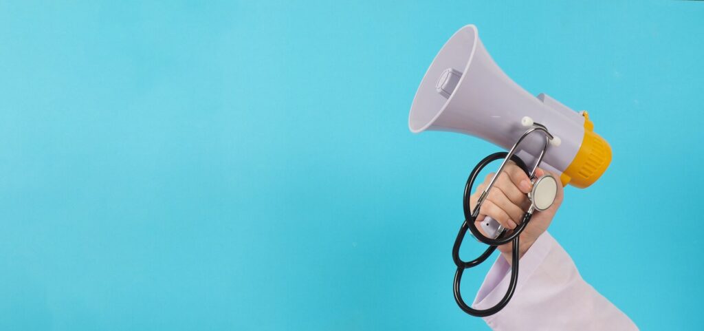 doctors-hand-is-holding-megaphone-stethoscope-blue-background